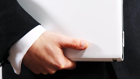 Büroarbeit (Symbolbild) Hand einer Person in Geschäftskleidung hält eine Akte.