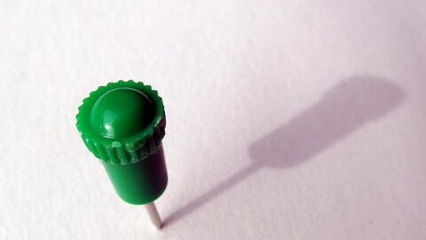 Grüner Pin steckt in einer weißen Fläche.