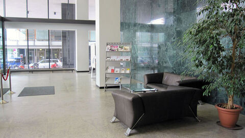 Im Eingangsbereich des Oberlandesgerichts steht eine Sitzgruppe, eine Pflanze und ein Ständer mit Infomaterial.