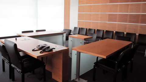 Auf dem Tisch eines menschenleeren kleinen Sitzungssaals stehen zwei Telefone.