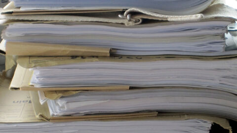 Das Bild zeigt nachlässig aufeinandergestapelte Akten.