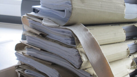 Das Bild zeigt nachlässig aufeinandergestapelte Akten.