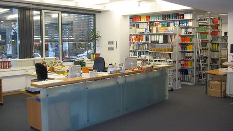 Blick auf die Arbeitsplätze der Bibliothek, im Hintergrund Bücherregale.