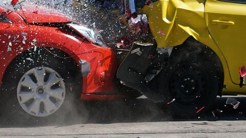 Ein rotes und ein gelbes Auto stoßen zusammen, es kracht.