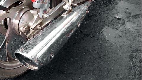 Auspuff an einem Motorrad, an der Seite ist ein Teil des Hinterrads zu sehen.