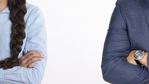 Eine Frau und ein Mann stehen mit verschränkten Armen mit Abstand nebeneinander.