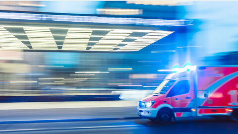 Rettungswagen fährt entlang einer beleuchteten Straße.