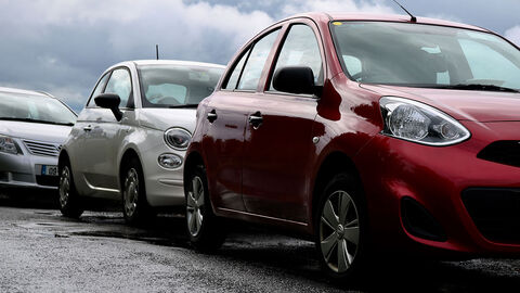 Drei parkende Autos stehen am Straßenrand.