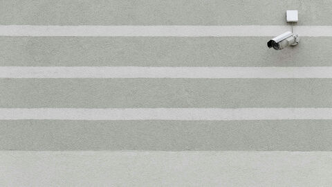 Eine auf einer mit grauen Streifen verputzten Wand montierte Überwachungskamera.