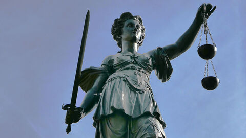 Justitia Justitia-Statue vor blauem Himmel.