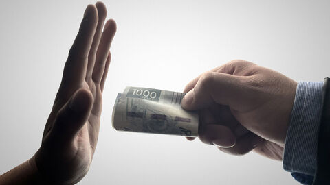 Korruptionsprävention Eine Hand bietet eingerollte Geldscheine an, eine weitere macht eine abwehrtende Geste.