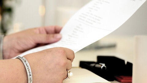 Ein beschriebenes Blatt Papier wird von zwei Händen gehalten.