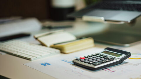 Schreibtisch mit Abrechnungsunterlagen und Rechner.