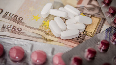 Tabletten und Dragees liegen auf einem Geldschein.