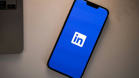 Smartphon, auf dem das LinkedIn-Logo zu sehen ist, liegt auf einem Schreibtisch.