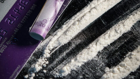 Mehl, das aussieht wie Kokain mit Scheckkarte und Geldschein auf einer schwarzen Platte.